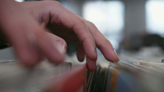男性双手穿过乙烯基唱片收藏，特写镜头。