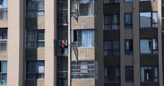 高空作业的工人在高楼外墙维修空调