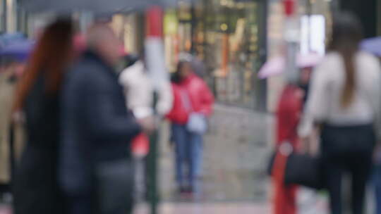 一群人打着伞漫步在雨中的城市街道上热闹的