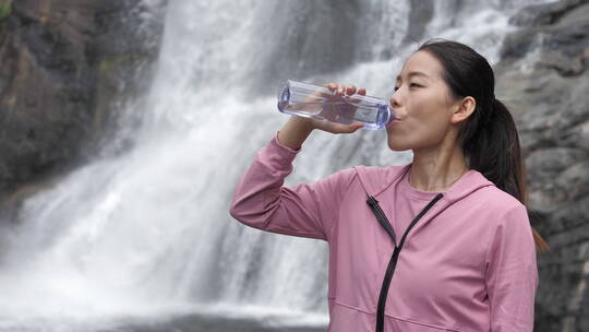 亚洲中国人女性在瀑布下喝水饮用水