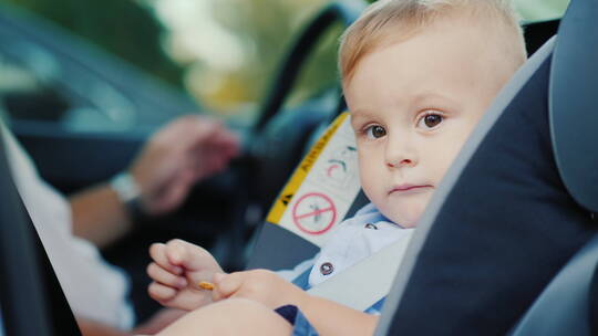 小男孩坐在父亲旁边的汽车座位上