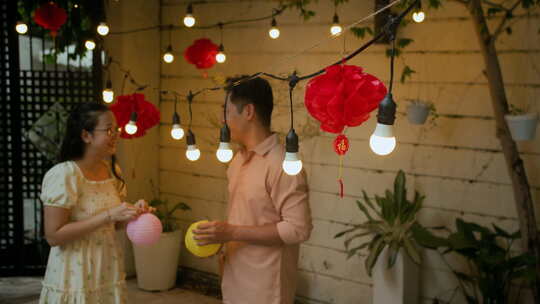 亚洲夫妇在中秋节用灯笼装饰后院