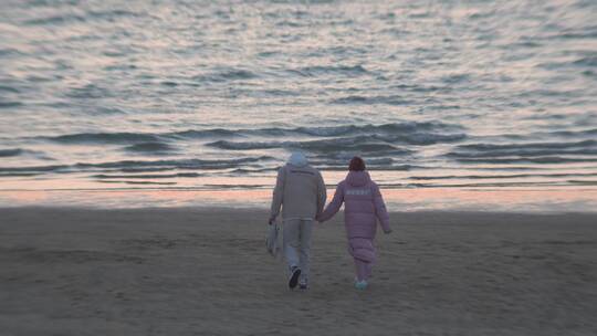 海边沙滩上散步的情侣