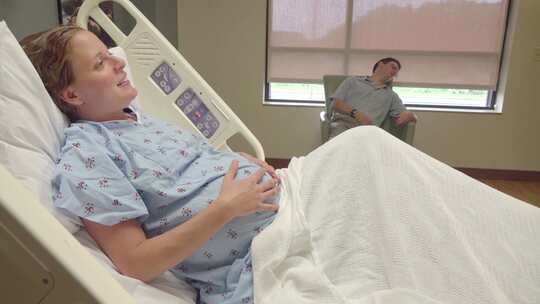 躺在病床上试图引起丈夫注意的妇女抱着怀孕