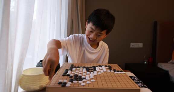 可爱的男孩在窗边下围棋