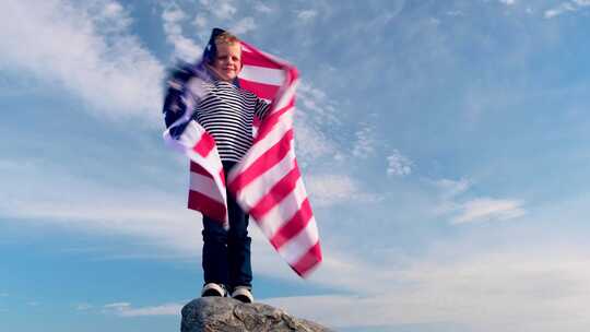 夏季美国国旗之国，金发男孩在蓝天上挥舞美国国旗