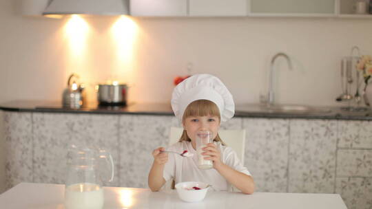 小女孩坐在厨房里吃冰淇凌喝牛奶
