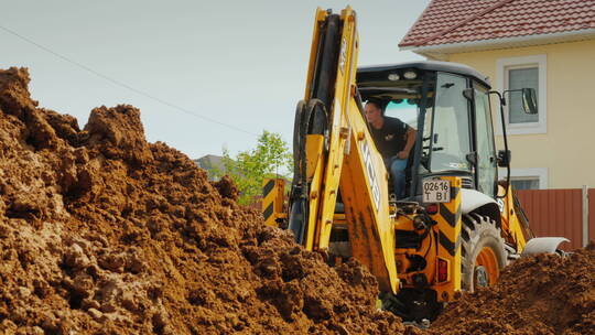 挖掘机在私人别墅附近挖掘沟渠视频素材模板下载