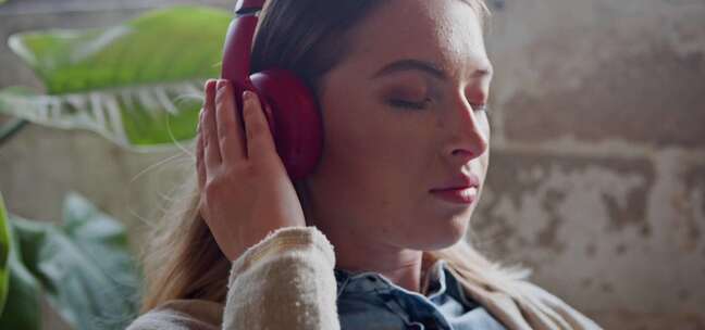 女人一边听音乐一边把耳机贴在耳朵上