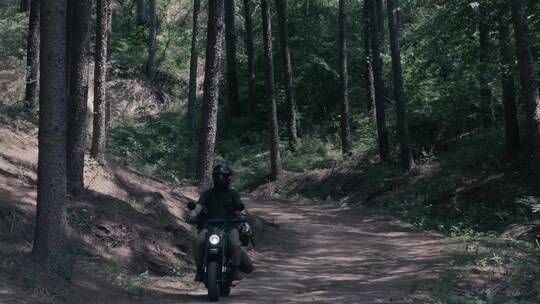 男子在森林山路上骑摩托车