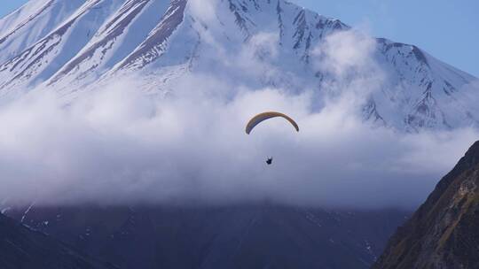 雪山下滑滑翔伞的人