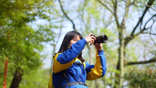 阳光明媚的春天年轻女孩拿着相机在路上拍照