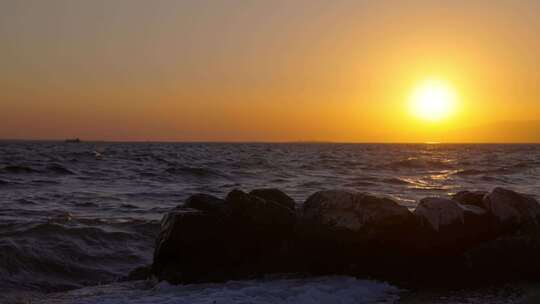 夕阳西下海浪拍打礁石海潮海面海船