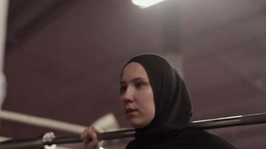 坚定的穆斯林女运动员用杠铃锻炼