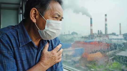 老人戴口罩窗边抚胸望工厂