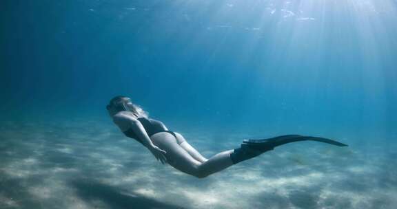 女子自由潜水员在蓝海水下游泳女子在水下用