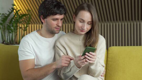 一对情侣看着手机上的好消息共同庆祝胜利视频素材模板下载