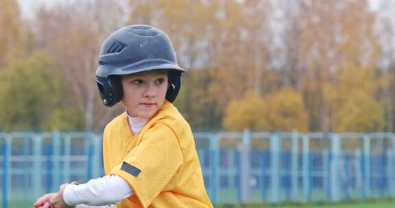一个小男孩穿着防护装备在等待击球