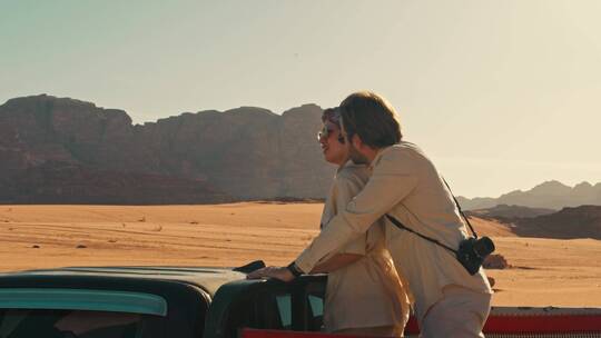 情侣站在越野车上欣赏沙漠风景
