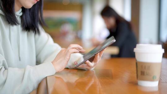 年轻女子在咖啡店使用平板电脑上网