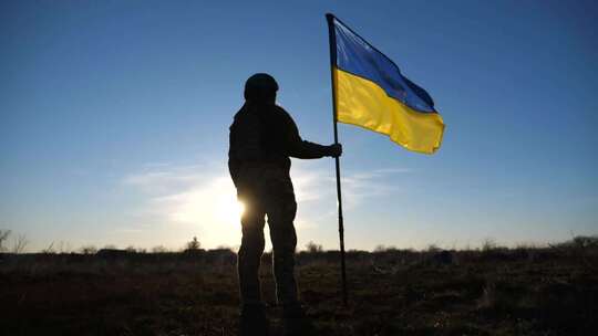 乌克兰女陆军士兵手持乌克兰国旗，背景是太