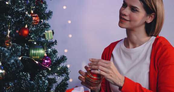 一个漂亮的女人正在家里为圣诞晚会装饰一棵松树。