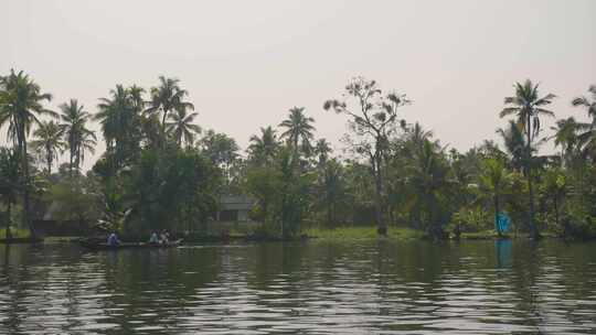 相机在喀拉拉邦西部穷乡僻壤的一艘运河小船上由三个人在远处航行视频素材模板下载