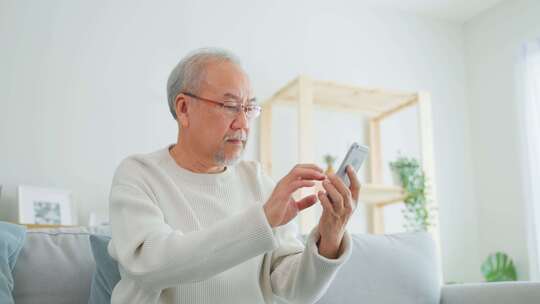 老年男性在家中使用手机视频素材模板下载