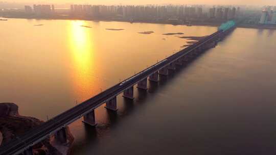 黄昏日落下的高铁穿过城市跨江大桥