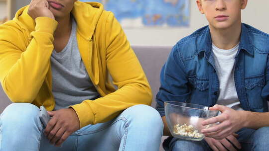 两个无聊的大学生看日间电视肥皂剧，吃爆米花视频素材模板下载