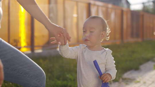 蹒跚学步的孩子在户外用手带女人