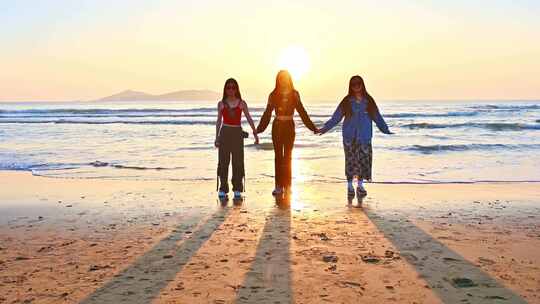 三个亚洲年轻漂亮美女站在大海边拍摄日出
