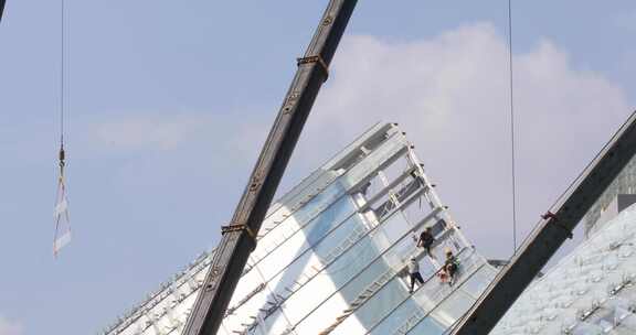 建筑工人城市高空安装作业 玻璃顶蓝天背景