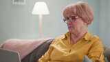 疲惫的戴眼镜的老年妇女坐在沙发上治疗近视高清在线视频素材下载