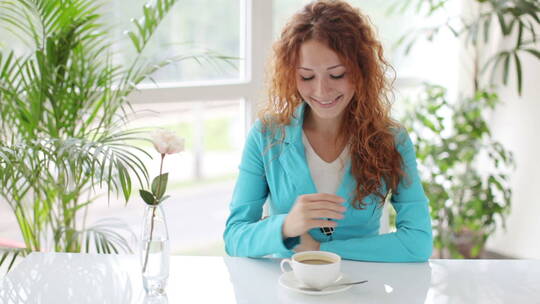 女人坐在桌旁喝咖啡微笑视频素材模板下载