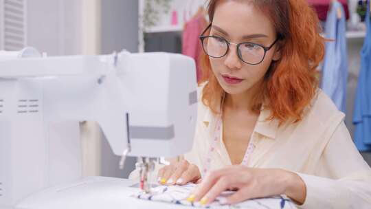 亚洲美丽的裁缝女人在裁缝工作室做衣服。