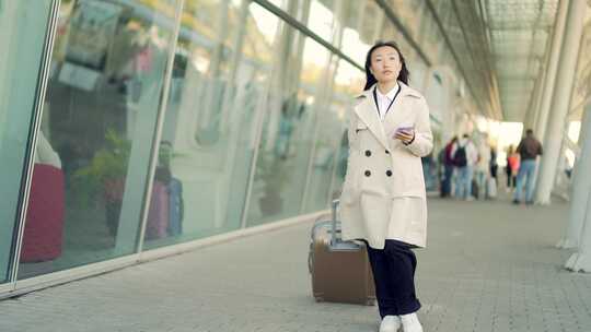 亚洲女旅游女商人带着手提箱从航站楼机场背
