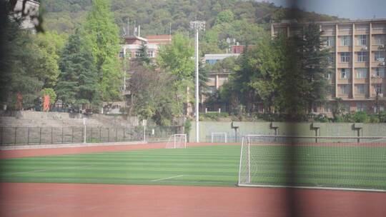 隔着护栏拍摄校园运动场足球场视频素材模板下载