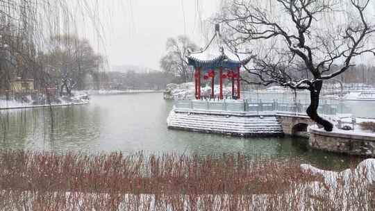 风雪中的湖面挂着红灯笼的古代建筑六角凉亭