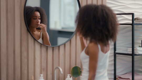 非洲裔美国妇女用牙膏牙刷刷白牙照镜子女孩视频素材模板下载