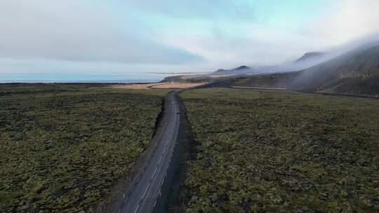 无人机拍摄的冰岛冬季苔藓地里汽车行驶的照