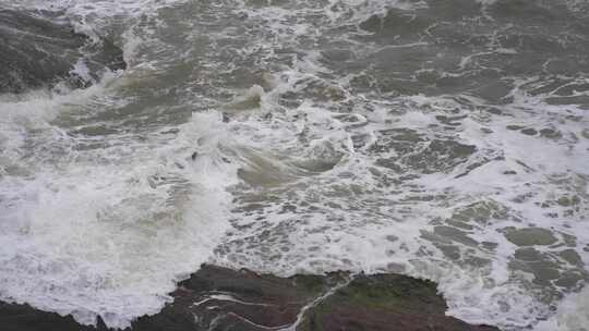 海浪拍打岩石浑浊海水冲刷礁石浪花阴天大海