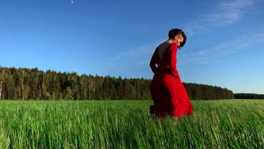 穿着猩红色连衣裙在风中流动的年轻女模特。