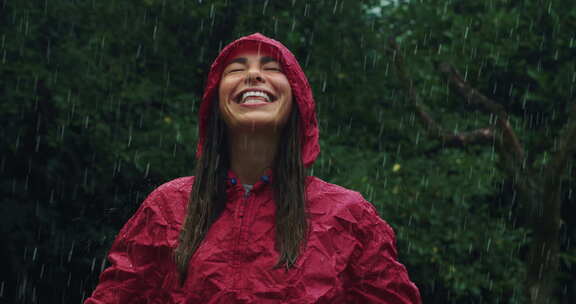 穿着雨衣享受雨水的快乐女人肖像