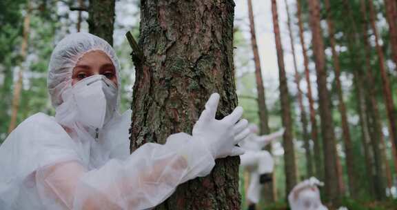 穿着防护服的女人在森林里跳舞和拥抱树木