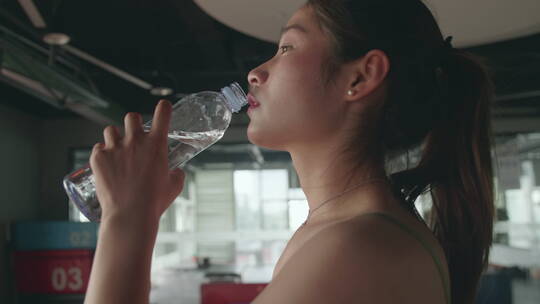 健身房里锻炼身体喝水的亚洲女孩视频素材模板下载