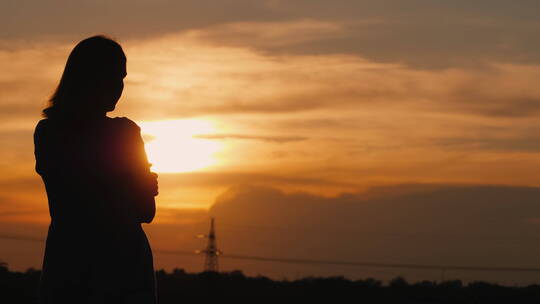 夕阳下一个女人凝视远方的孤独剪影