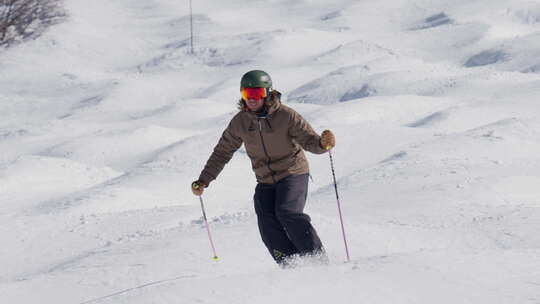 男子带着滑雪杖在山坡上滑雪