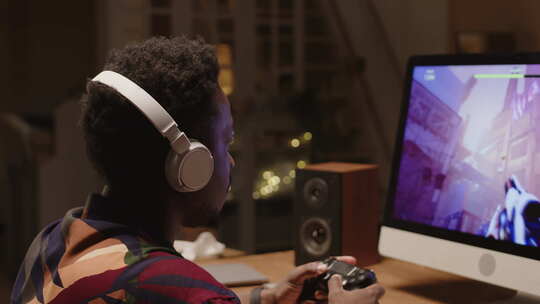非裔美国男性玩家晚上在PC上玩FPS游戏