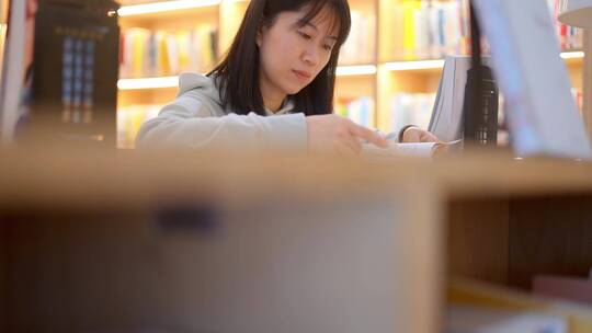 年轻女子图书馆在书架前翻看书本学习